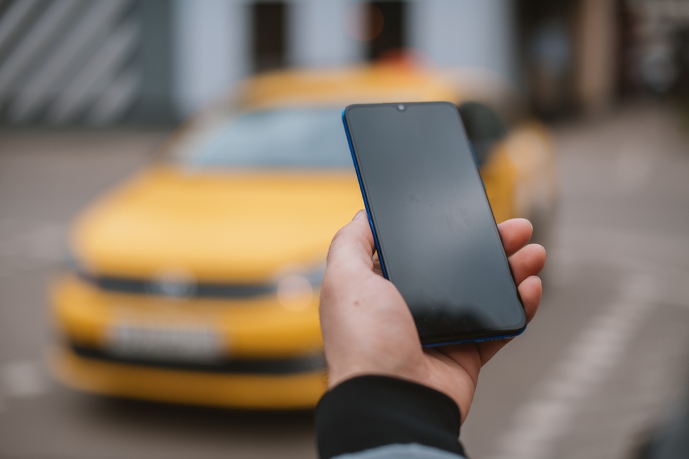 mano de hombre sosteniendo celular mientras pide un taxi